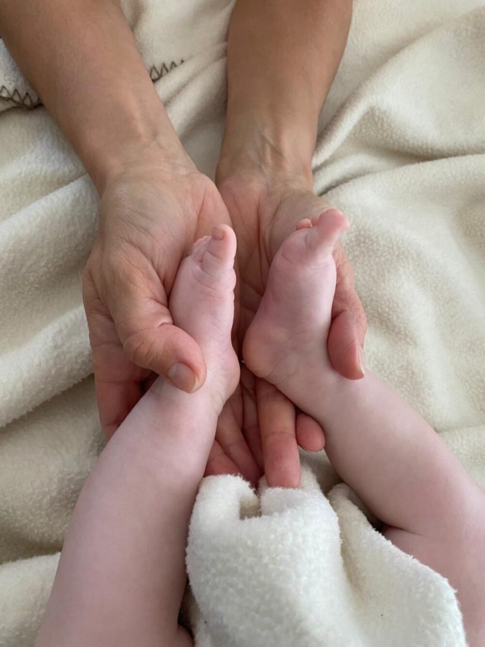 Babymassage – Hände einer Mutter mit Babyfüßen